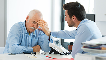 Sad older worker and younger one talking in office